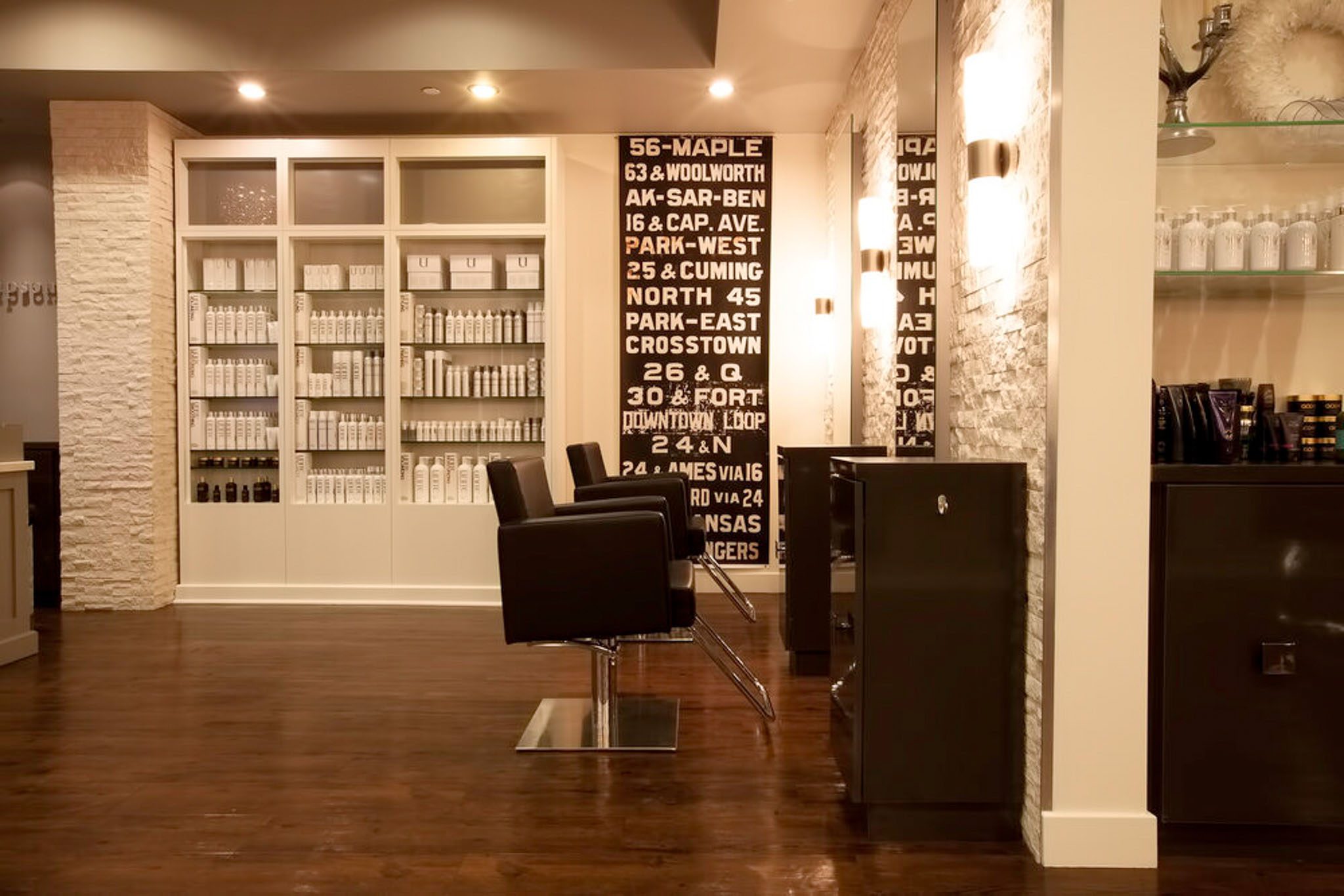 A modern hair salon interior with styling chairs, shelves of hair products, and wall decor featuring large text.