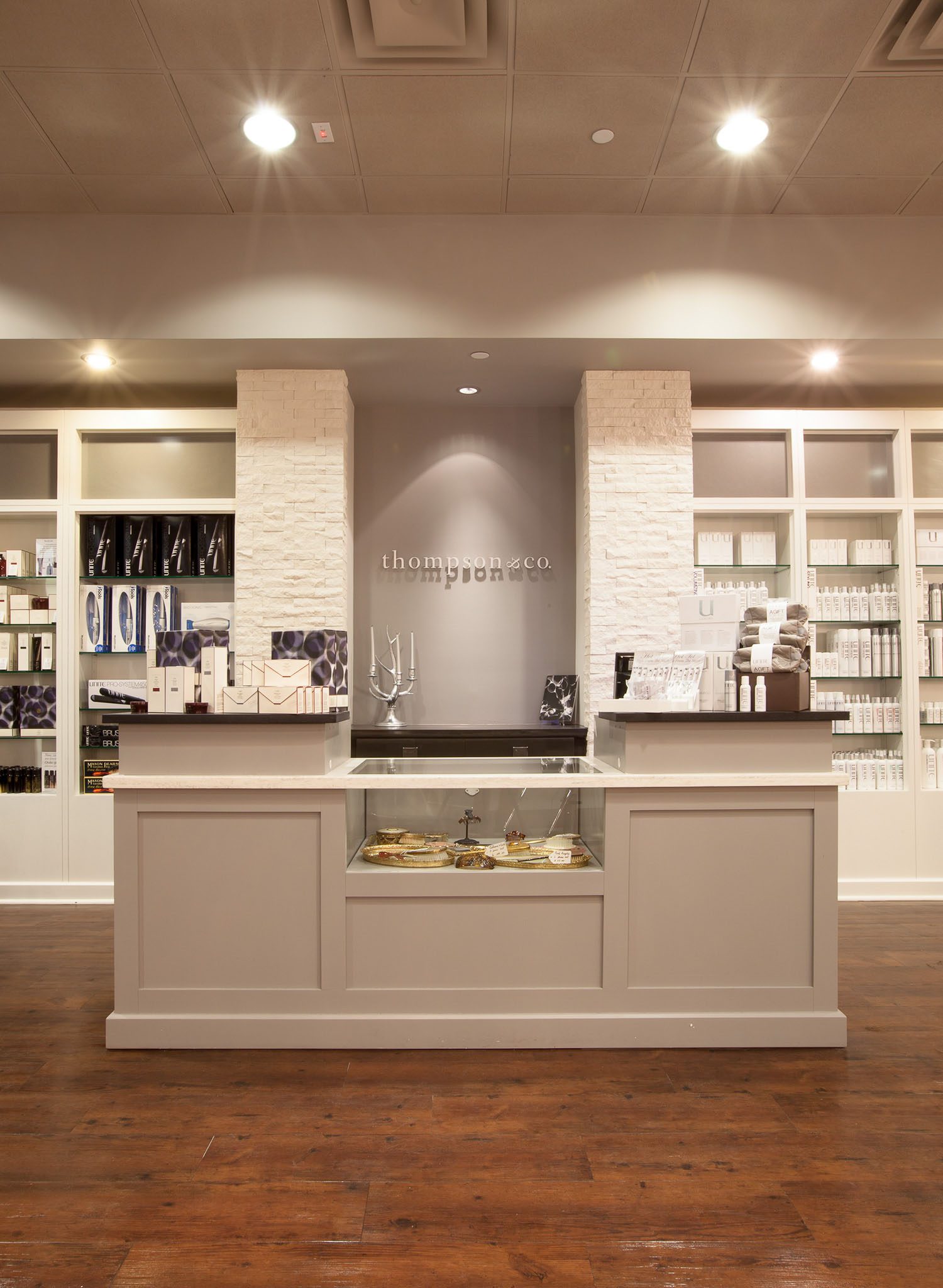 A modern spa reception area with product displays, a central counter, and white brick accents.
