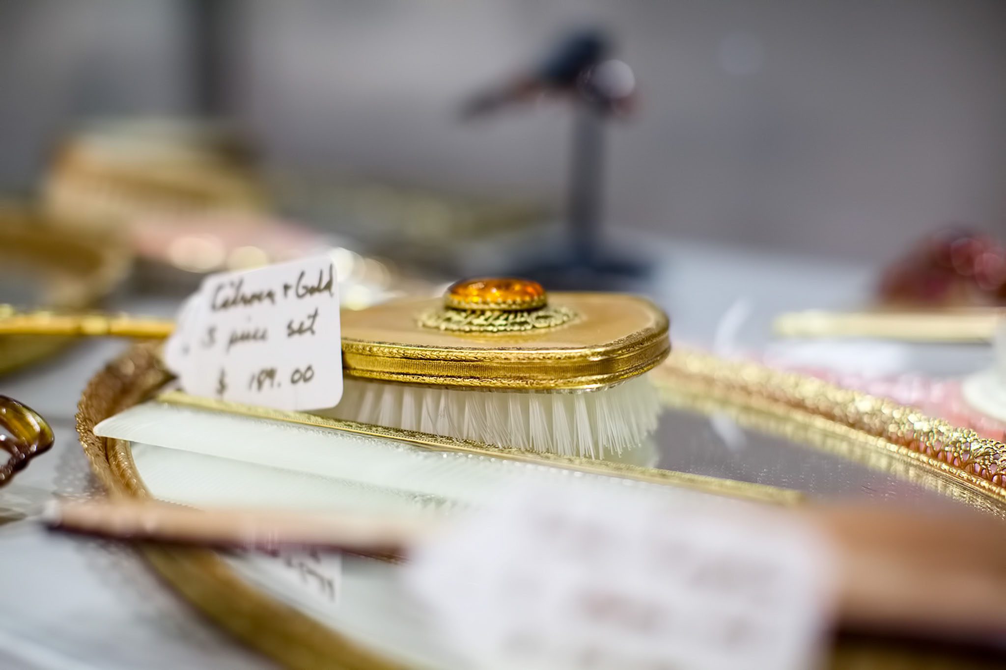 Vintage gold hairbrush set with a price tag of $99.00 displayed on an ornate tray.