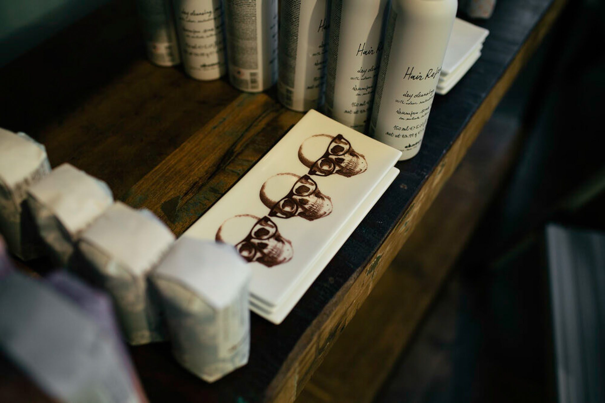 Stacked printed napkins with skull designs, surrounded by various bottles on a wooden surface.