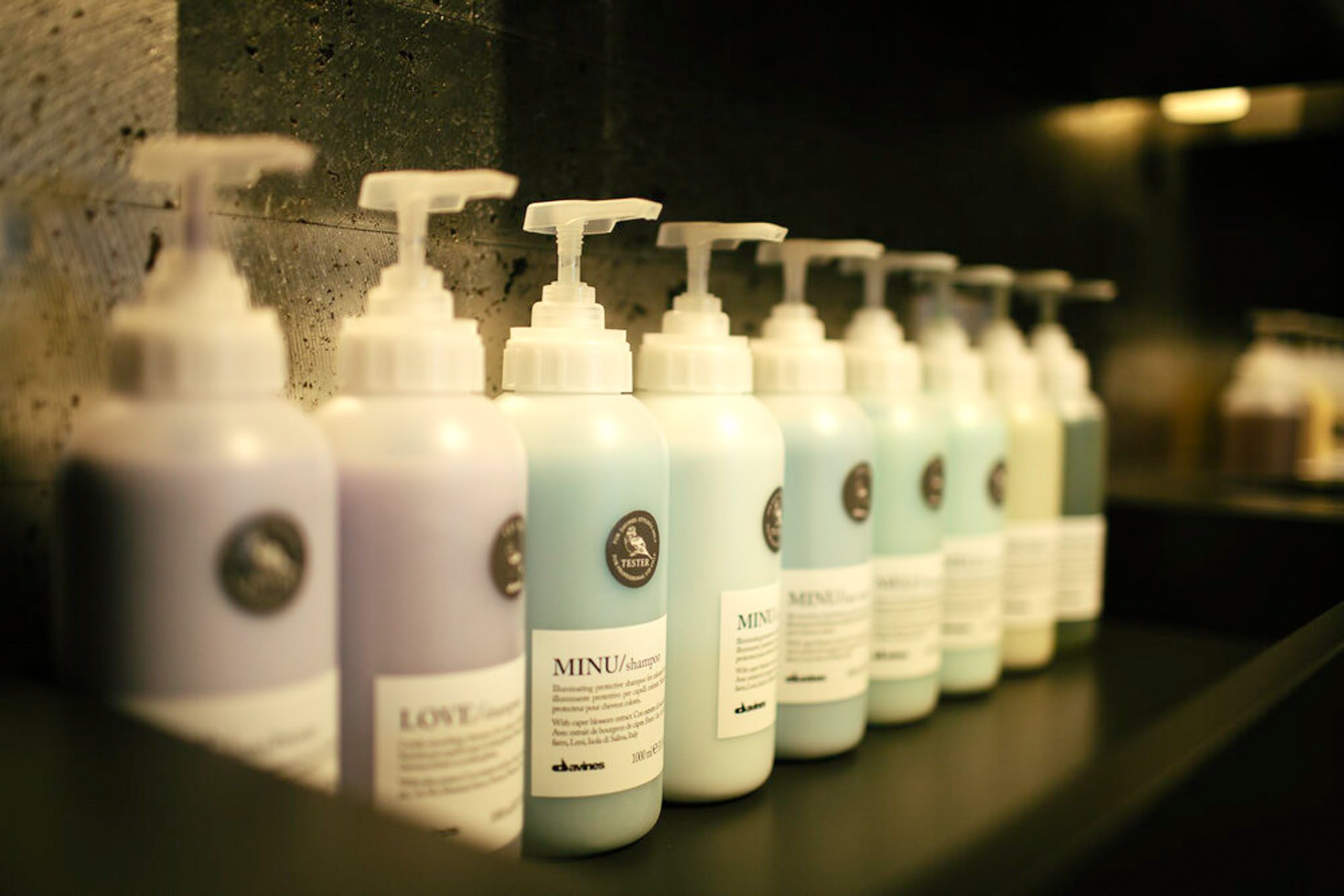 A row of Davines hair care products in pump bottles, arranged on a dark shelf.