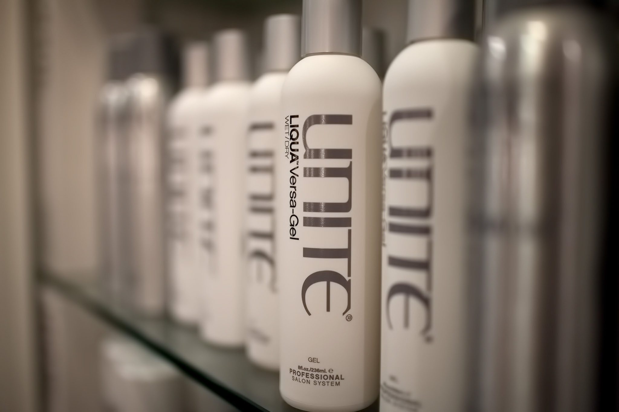 Bottles of Unite Liquid Volume Gel are lined up on a shelf, displaying their labels and branding.