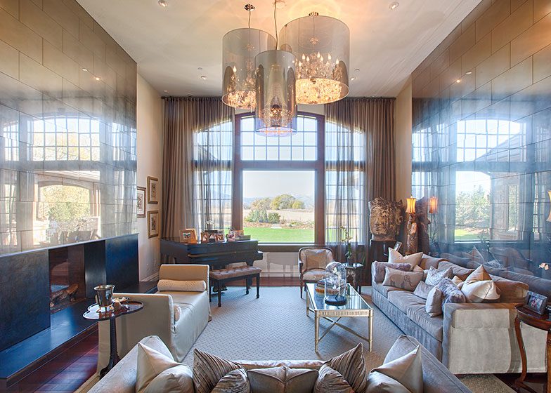 A luxurious living room with large windows, a grand piano, chandeliers, and elegant furnishings.
